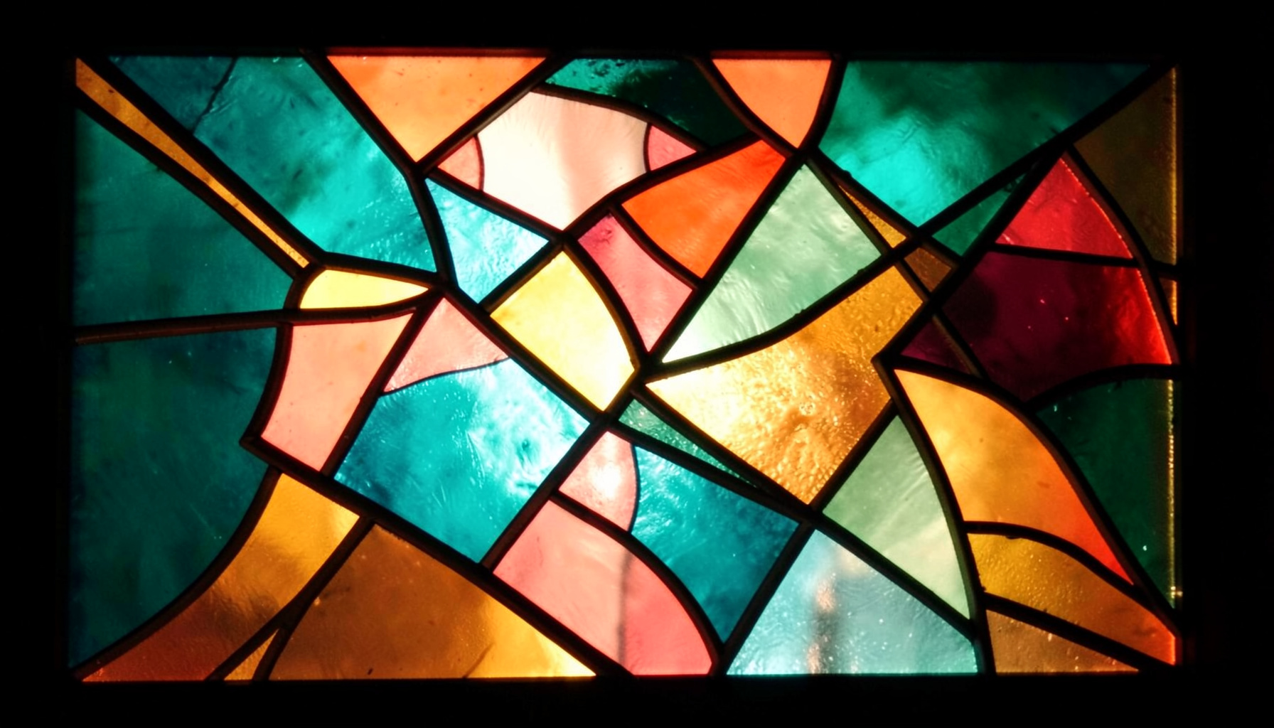 A stained-glass composition with bold leaded segments in deep teal, coral, and amber, forming an abstract geometric pattern that suggests interconnected ideas